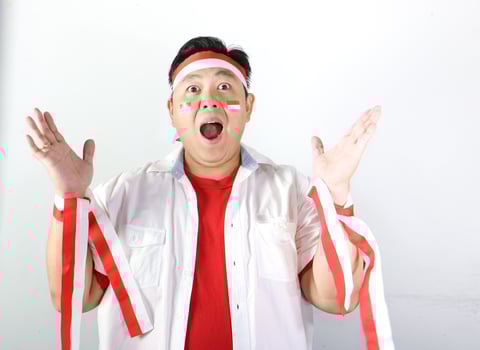Excited Indonesian Man wearing red and white headband with both hands open and mouth open saying WOW photo