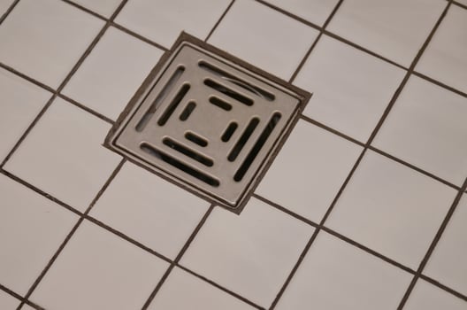 Close-up of Square Metal Drain Cover on Tiled Floor photo
