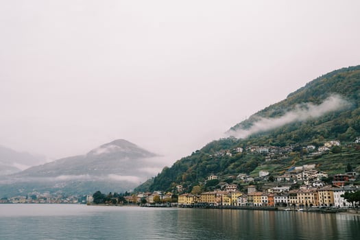 Colorful villas at the foot of forested mountains in the fog on the shores of Lake Como. Italy photo