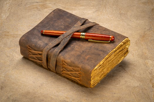 retro leather bound journal with decked edge handmade paper pages and a stylish pen, journaling concept photo