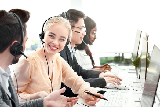 Smiling customer support workers communicating to solve client's problem together at call centre office. Positive hotline operators with headsets having conversation at workplace photo