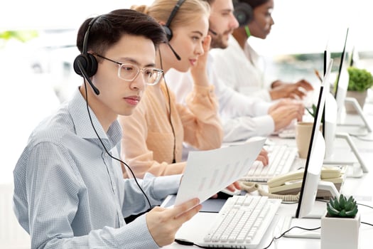 Asian hotline operator working with documents, providing technical support services to clients, free space. Call centre representatives talking to customers or selling goods online photo