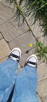 Blue jeans and black and white shoes view from top photo