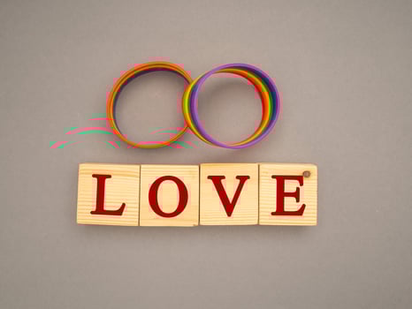 Rainbow patterned wristbands and wooden cubes with the text LOVE on a gray background photo