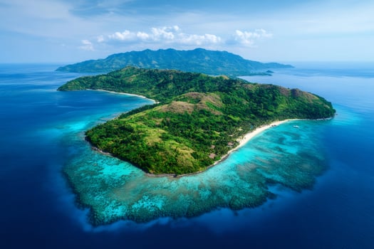 Tropical island with turquoise water and coral reef surrounding lush vegetation in the Philippines photo