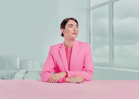 a woman in a pink suit sitting at a table photo