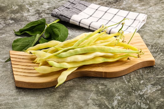 A wooden cutting board with beans and leaves photo
