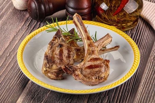Grilled lamb chops on a white plate with rosemary photo