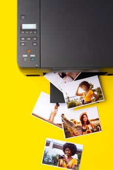 Printer printing colorful photos of people close up, yellow background