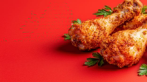 Crispy Fried Chicken Delight A Delectable Still Life Featuring Golden Brown Chicken Drumsticks Arranged Artfully Against a Vibrant Red Background, Perfect for Culinary Enthusiasts and Food Bloggers photo