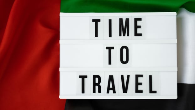 Lightbox with text TIME TO TRAVEL on background of waving UAE flag made from silk. United Arab Emirates flag with concept of tourism and traveling. Inviting greeting card, advertisement. Dubai welcoming card photo