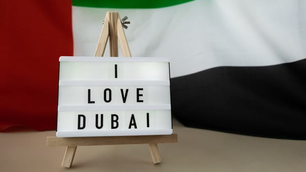 Message text I LOVE DUBAI on background of waving UAE flag made from silk. United Arab Emirates flag with concept of tourism and traveling. Inviting greeting card, advertisement. Dubai welcoming card photo