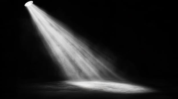 A dramatic spotlight beam illuminates a darkened stage or space, creating a focused point of interest and theatrical atmosphere. photo