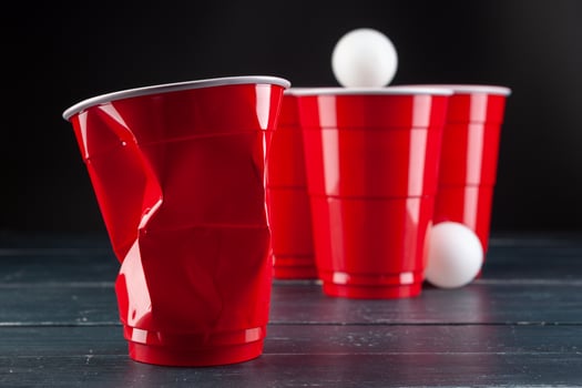 Wooden table with red cups and ball for beer pong photo