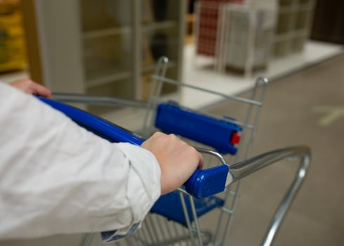 Closeup of woman's hands pushing a shopping cart. Woman with trolley in supermarket close-up. Supermarket Shopper photo