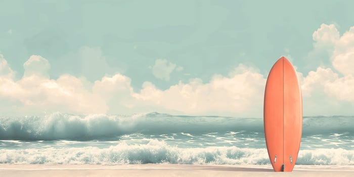 A vibrant orange surfboard stands on the shore, framed by gentle waves under a serene blue sky. photo