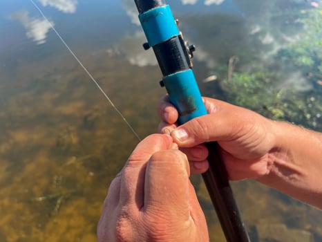 Fisherman putting bait on hook while fishing in river photo