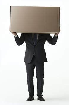Businessman in suit holding large cardboard box above head isolated on white background photo