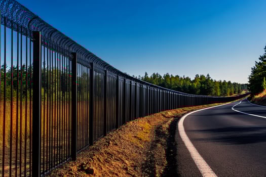 High security fence protecting highway infrastructure with razor wire in sunny day photo