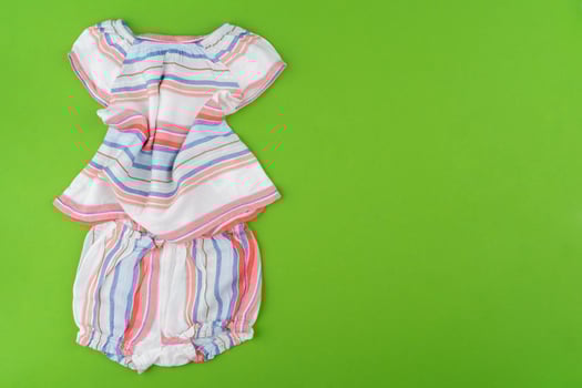 Top view of baby clothes on green background photo