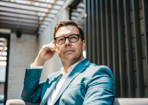 a man in glasses sitting on a couch photo