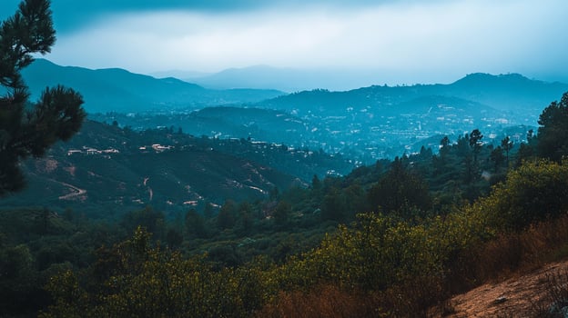 Misty mountain landscape with layered hills, distant town, and lush vegetation under an overcast sky. Serene nature view. photo