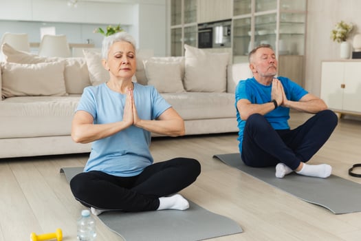 Yoga mindfulness meditation. Senior adult mature couple practicing yoga at home. Mid age old husband wife sitting in lotus pose on yoga mat meditating relaxing. Family doing breathing practice photo