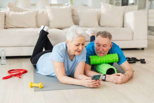 Yoga fitness training online. Senior couple practicing yoga fitness with online lessons on smartphone. Old wife husband watching training on phone before workout. Family doing sports exercise at home photo