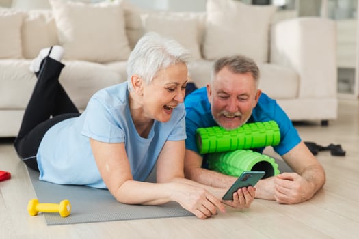 Yoga fitness training online. Senior couple practicing yoga fitness with online lessons on smartphone. Old wife husband watching training on phone before workout. Family doing sports exercise at home photo