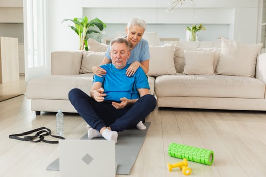 Yoga mindfulness meditation. Senior adult mature couple practicing yoga with online lessons in laptop. Old wife helping teaching husband meditating relaxing. Family doing breathing practice at home photo