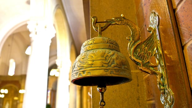 a golden bell hanging on a wall in a church photo