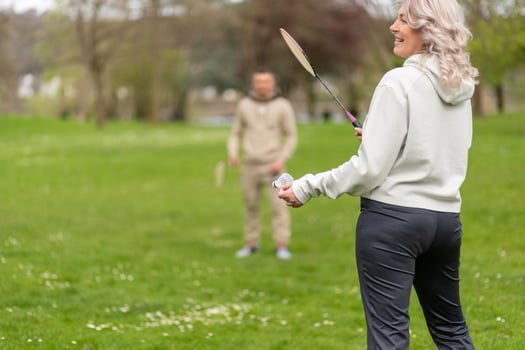 Woman playing badminton outdoors, man in distance photo