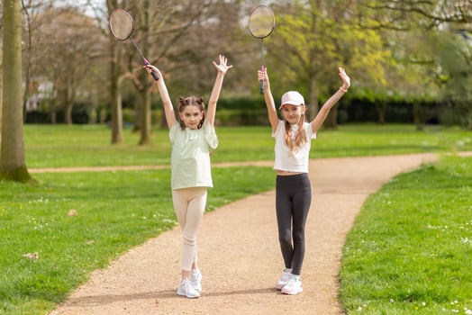 Two girls posing with badminton rackets in the park photo