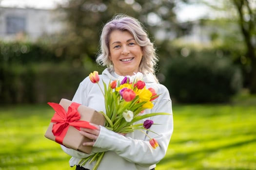 Happy smiling 50-year-old woman with tulips and gift photo