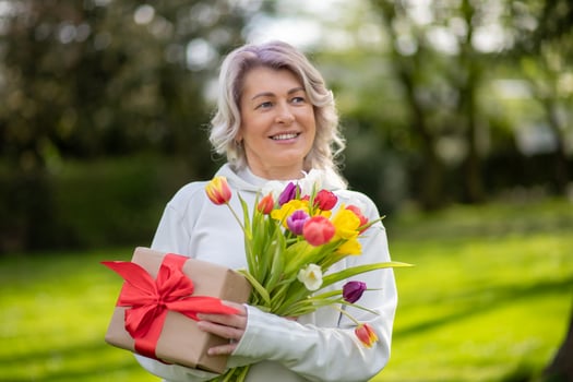 Happy smiling 50-year-old woman with tulips and gift photo