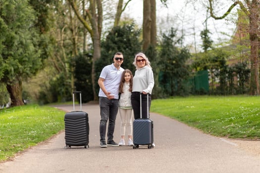Family of three with suitcases standing, facing the camera photo