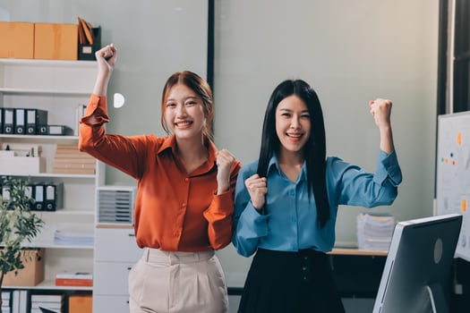 Two asian women in business attire celebrating photo
