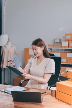 A woman is sitting at a desk with a laptop and papers photo
