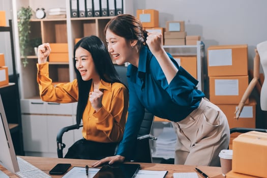 Two women in an office with their arms up photo