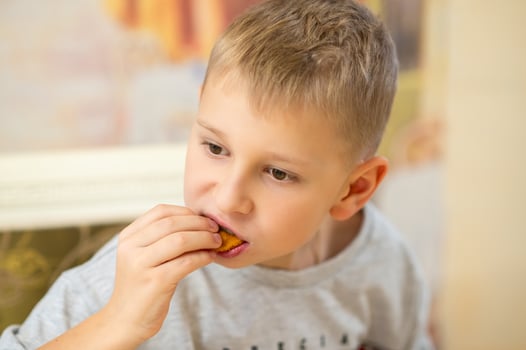 a young boy is eating a piece of food photo