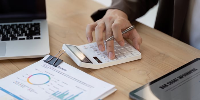 Budget analysis. Close-up of a hand calculating financial figures on a desk. photo