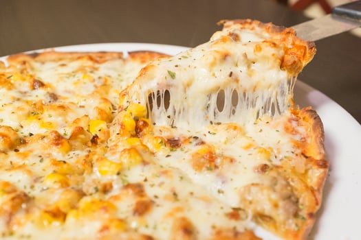 A slice of pizza with cheese and corn on it photo