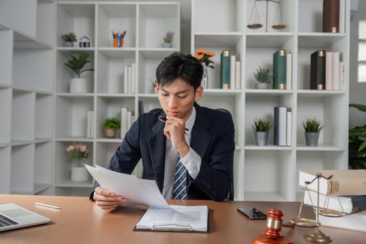 Thoughtful lawyer reviewing legal documents and notes, analyzing case strategy in modern office. photo