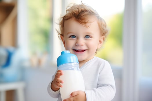 cute happy little baby holding a feeding bottle with milk and smiling. Milk formula for babies photo