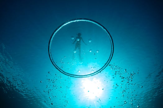 Bubble ring with diver swimming in blue water photo