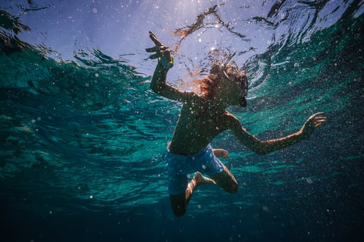 Preteen child in diving mask with snorkel swimming underwater photo