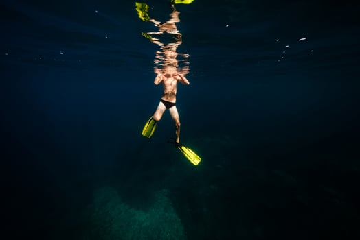 Anonymous fit man swimming undersea in sunlight photo