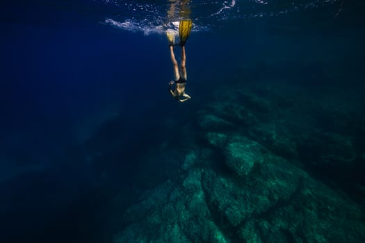 Anonymous young male swimmer diving in blue ocean photo