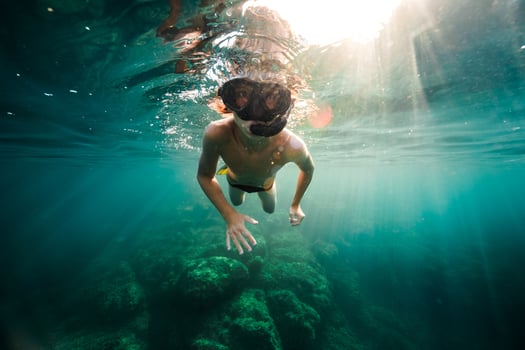 Young guy in snorkeling goggles swimming underwater of sea photo
