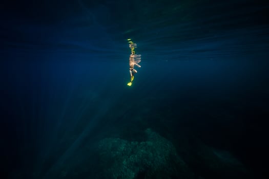 Anonymous man diving in deep blue ocean photo